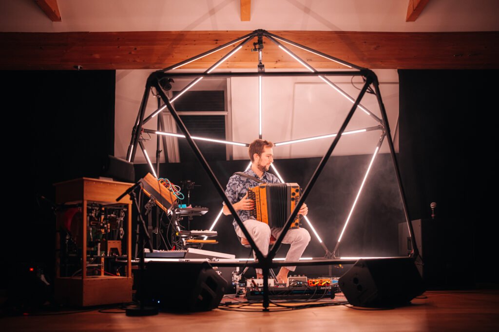Microcosm live: Jonny Kölbl mit Harmonika im Dome aus Lichtstäben