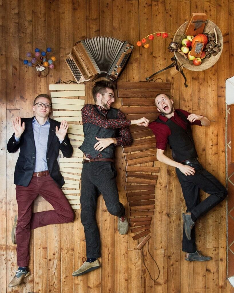 Quetsch ’n’ Vibes liegen mit Harmonika, Marimba und Obstschale auf einem Holzboden