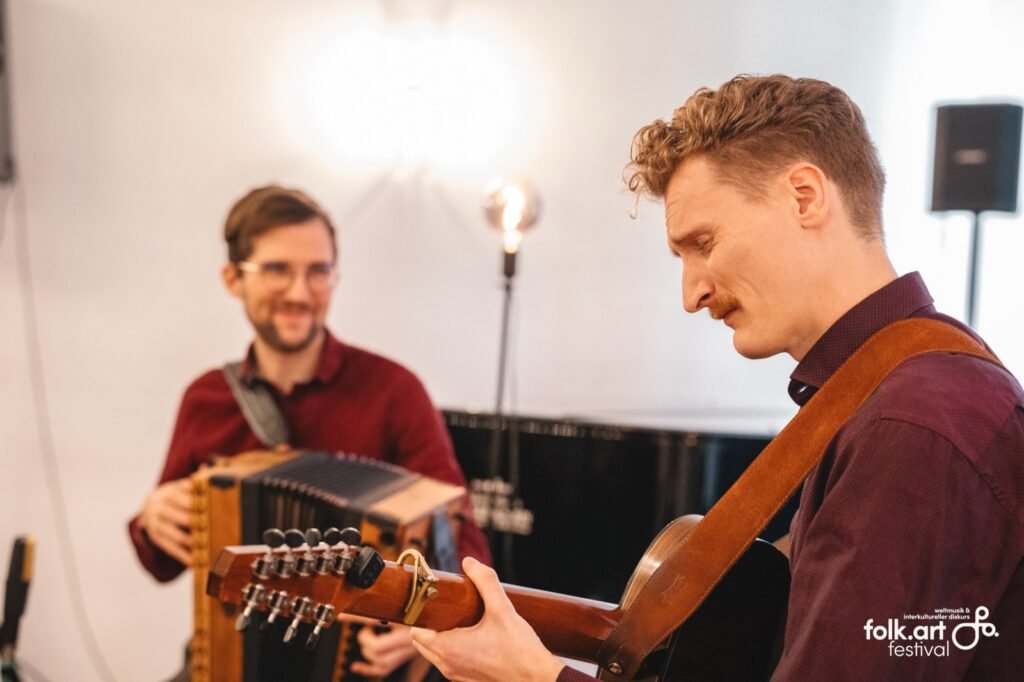 Tim & Jonnic spielen lachend Steirische Harmonika und Gitarre bei einer Matinee des folk.art Festivals